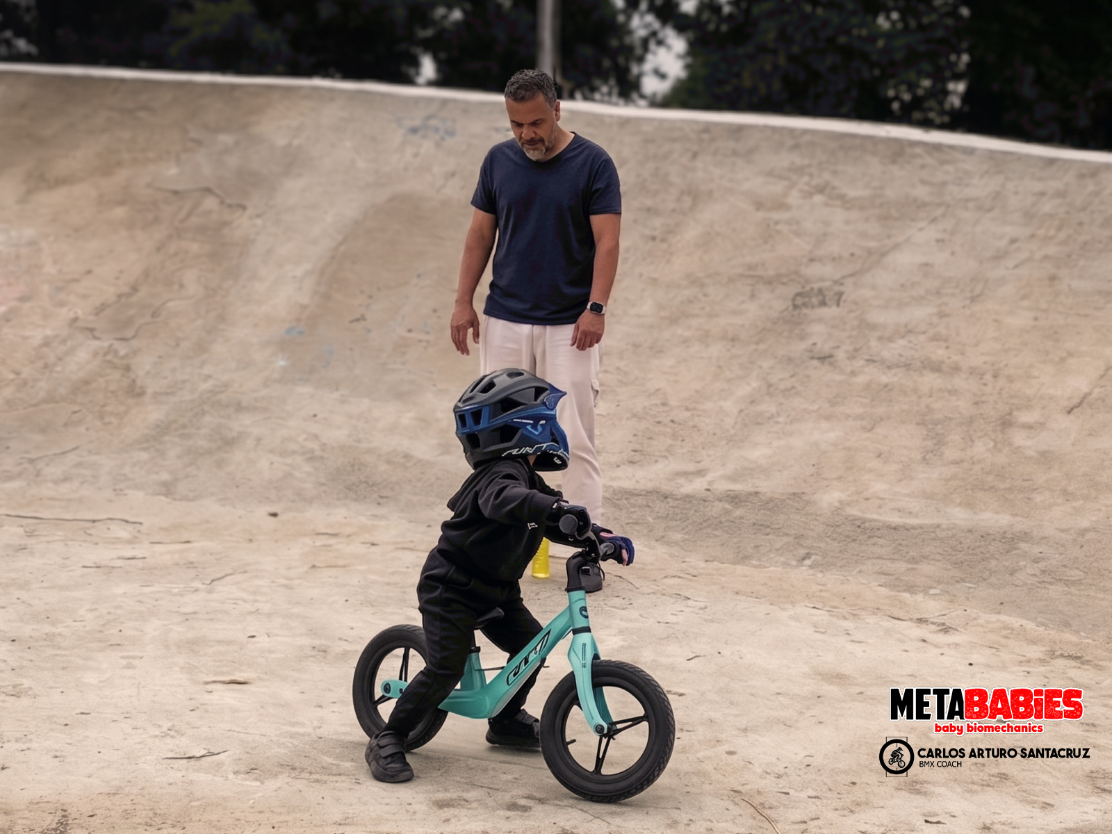 Entrenador acompañando a un niño pequeño en bicicleta de balance dentro de una pista